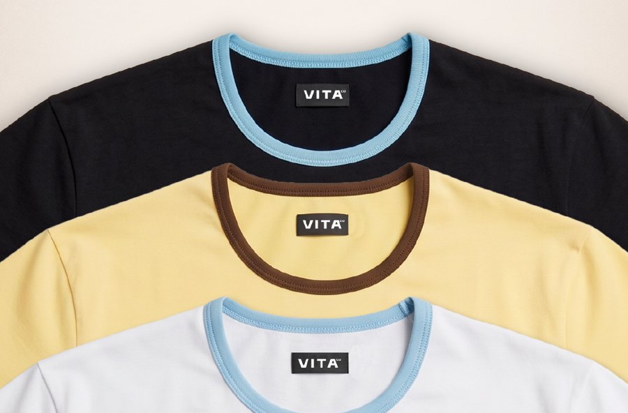Detalle de cuellos con vivo celeste y marrón en remeras negra, amarilla y blanca