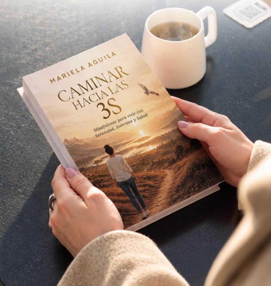 Manos sosteniendo el libro Caminar hacia las 3S junto a una taza de té.