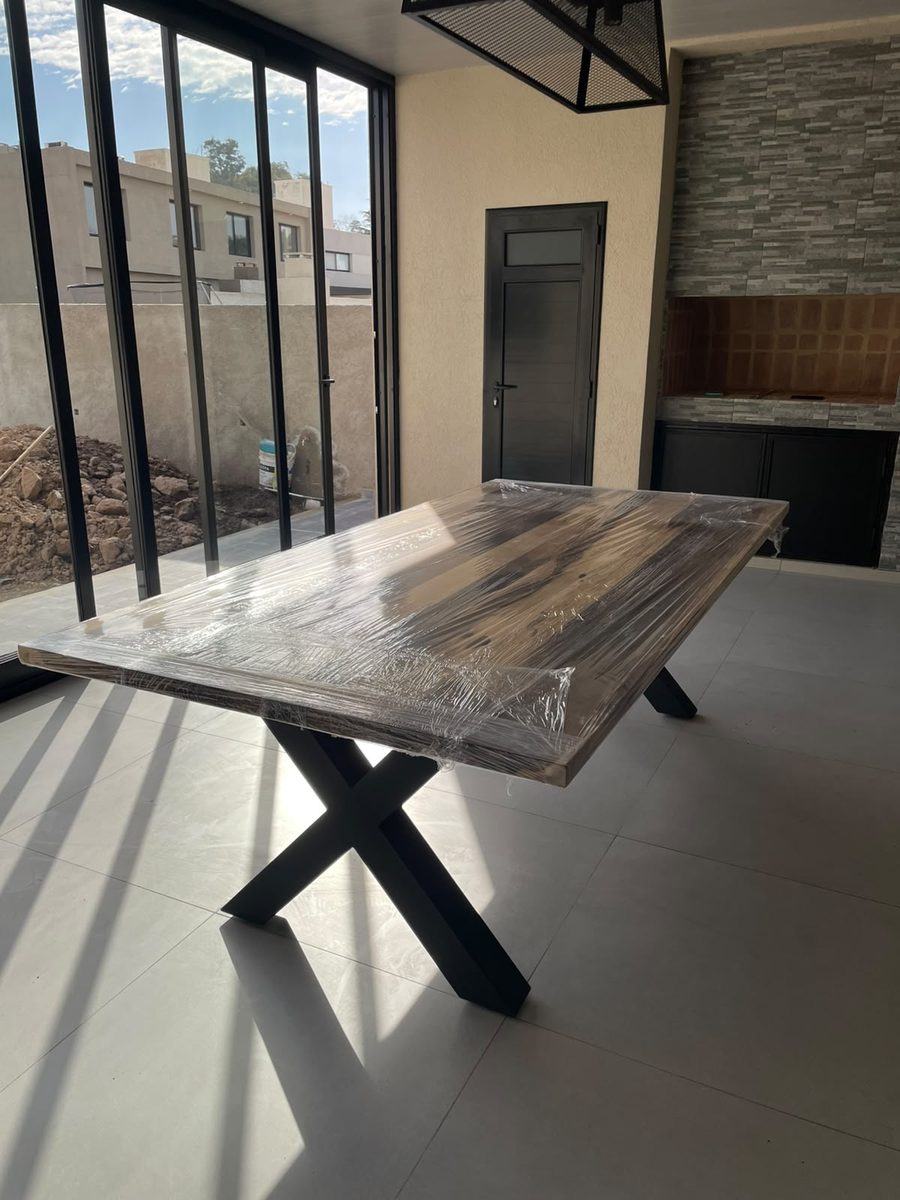 Mesa industrial de guayubira con base de hierro en X, recién entregada en un quincho