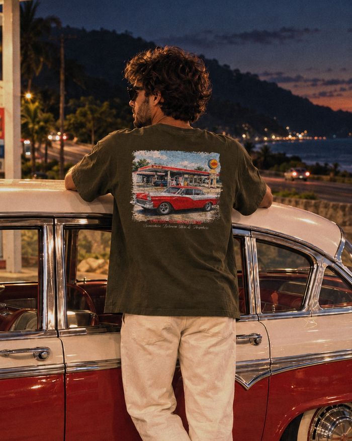 American Road Trip verde militar, com os braços no teto de um sedã clássico num posto antigo da Rio–Santos, em Ubatuba