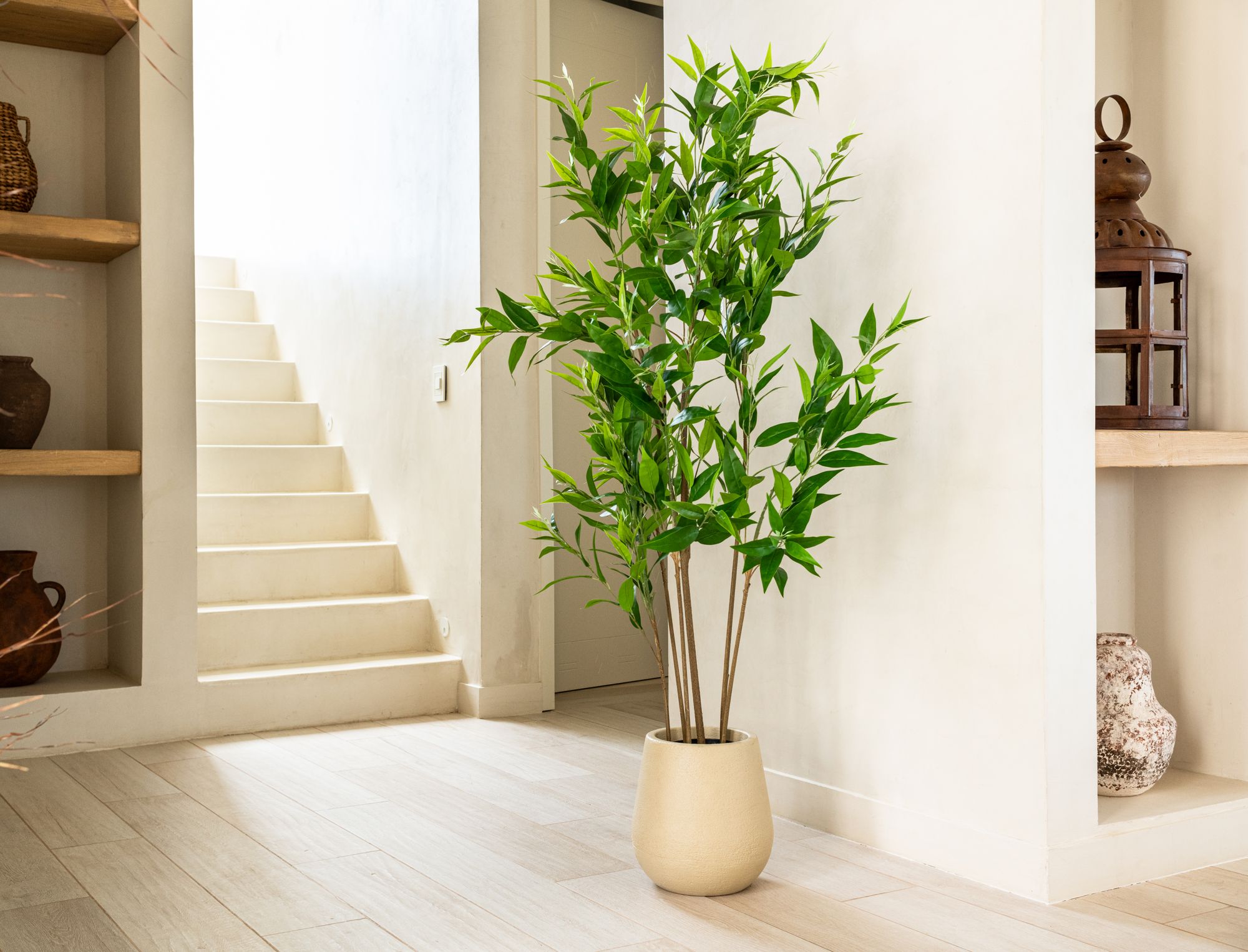 Planta artificial BRIZA Deco en maceta cerámica junto a una escalera