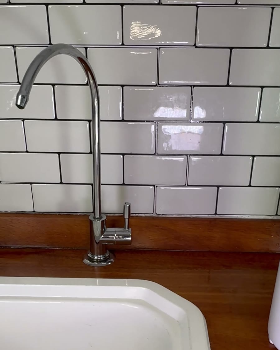 La canilla propia del purificador sobre una mesada con azulejos blancos