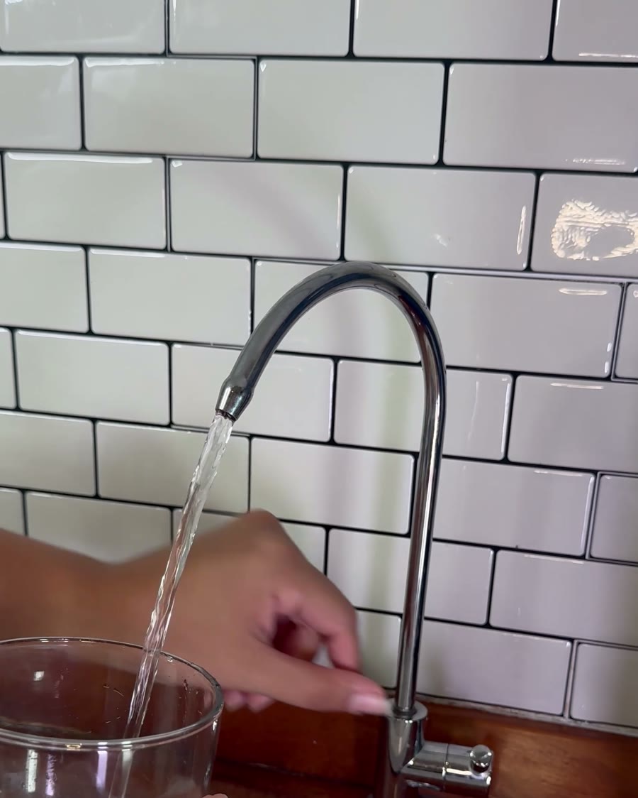 Llenando un vaso con agua de la canilla propia del purificador