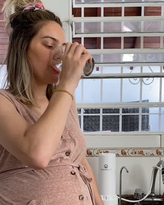 Una clienta tomando agua del Senic Out apoyado en su mesada