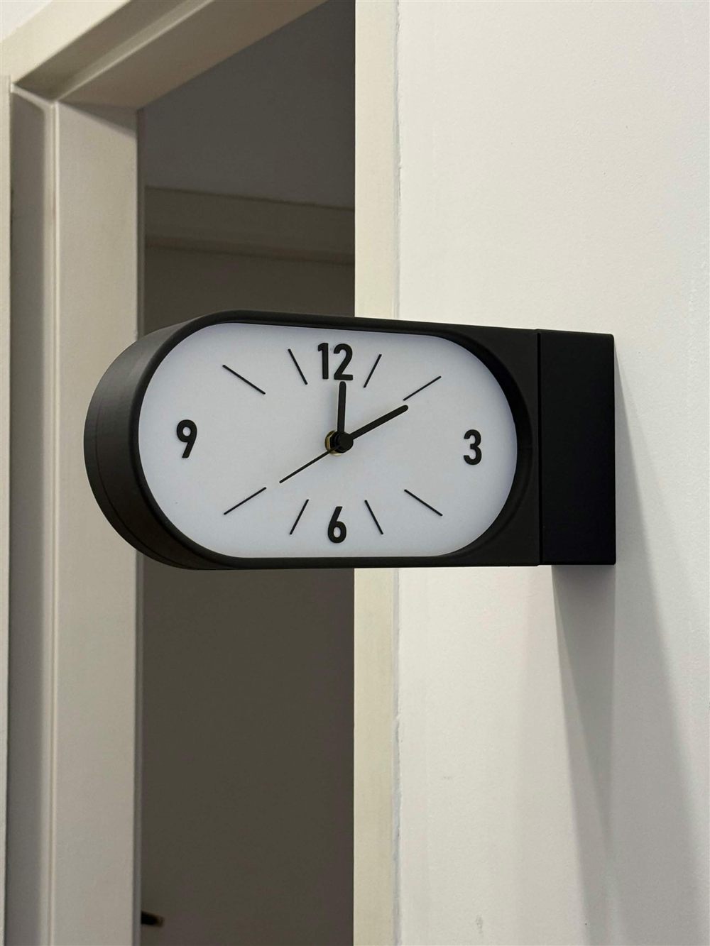 Reloj Doble Kansei negro instalado en pared clara