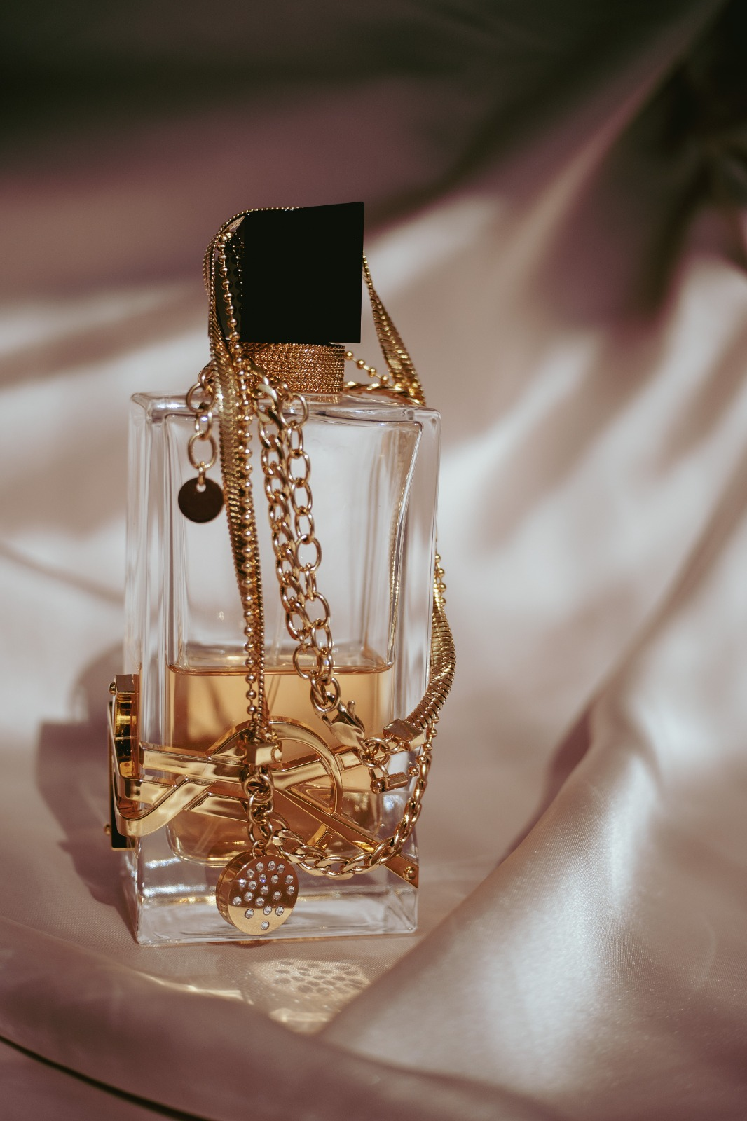 Scent Charm dorado junto a un frasco de perfume