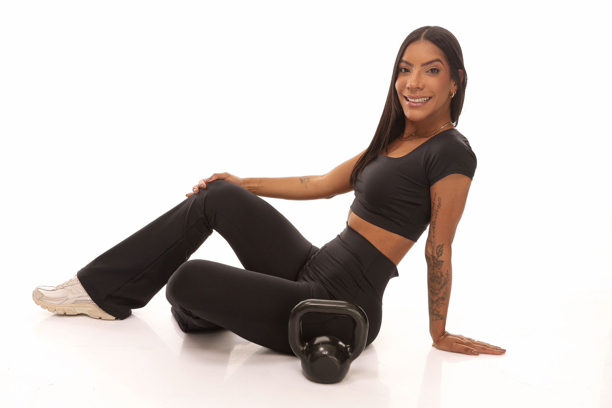 Mulher sentada usando calça flare e cropped pretos CAVELLE