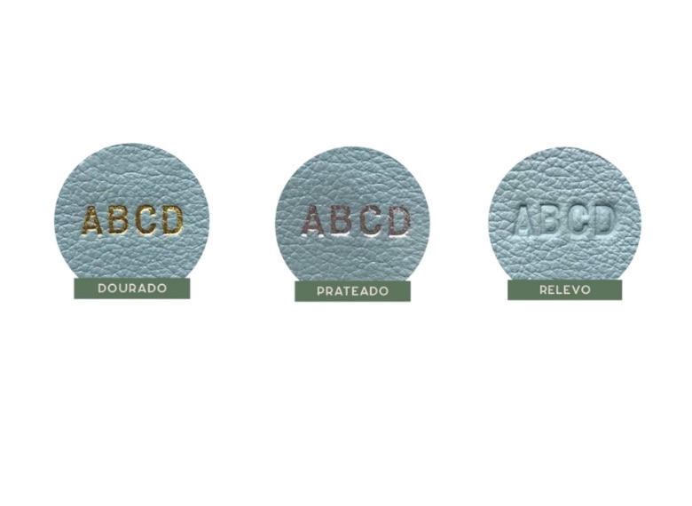 Três amostras redondas de couro azul-claro com as letras ABCD gravadas, uma para cada acabamento: dourado, prateado e relevo.